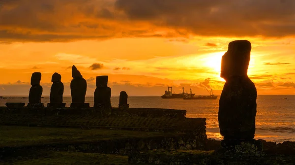 COPY SPACE: Sunset illuminates the moai statues and fishing boats in the back — Stock Photo, Image