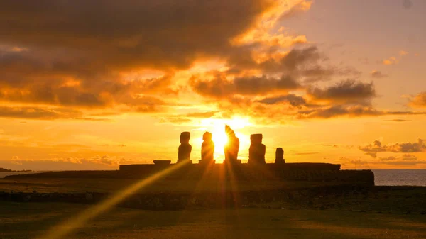 Piękne złote promienie słońca świecą na rząd rozpadających się starożytnych moai posągów — Zdjęcie stockowe