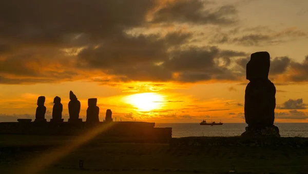 DRONE, SUN FLARE: Sceniczne ujęcie statku towarowego pływającego za posągami Moai. — Zdjęcie stockowe