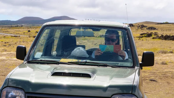 CLOSE UP: Мужской турист, сидящий в старом внедорожнике и читающий карту в пустыне — стоковое фото