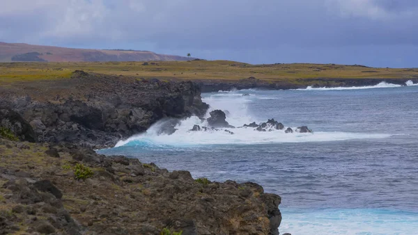 Глубоко-голубые океанские волны жестоко врезаются в черную скалистую береговую линию.. — стоковое фото