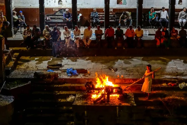 Gli indù locali guardano i loro parenti morti che vengono cremati in un fuoco aperto. — Foto Stock