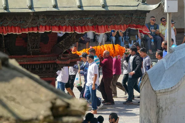 Muži nesou mrtvolu zabalenou do oranžové látky a květin před pohřebním rituálem — Stock fotografie