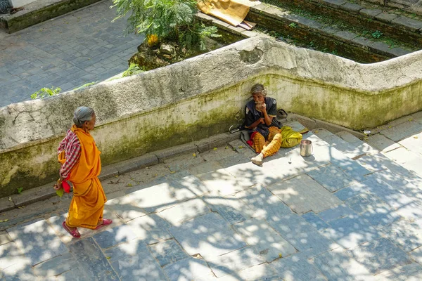 Γυναίκα μοναχός περπατά προς ένα ζητιάνο κάθεται από τις σκάλες μέσα στο Ναό Pashupatinath — Φωτογραφία Αρχείου