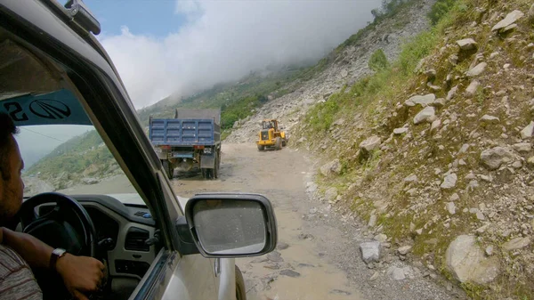 POV: Driving along bumpy road past small excavator fixing damage after landslide — Stock Photo, Image