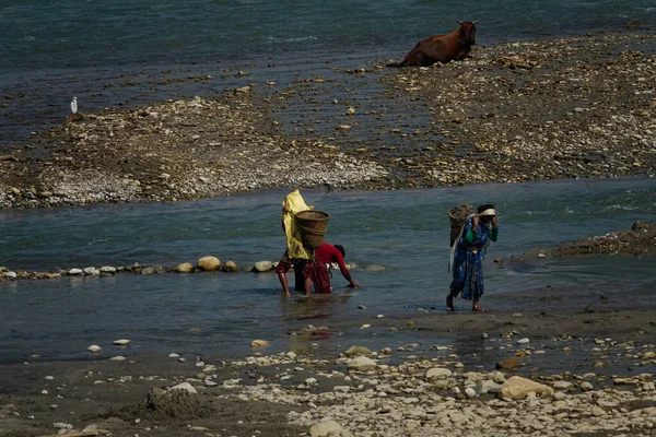 Mujeres locales llevan lodo desenterrado del río poco profundo en las cestas tejidas. — Foto de Stock