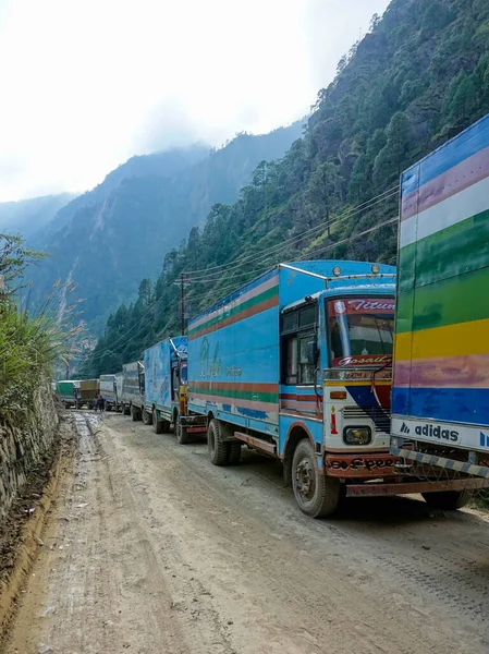 CLOSE UP: Colorful trucks queue up on the gravel road in the mountains of Nepal. — Stock Photo, Image