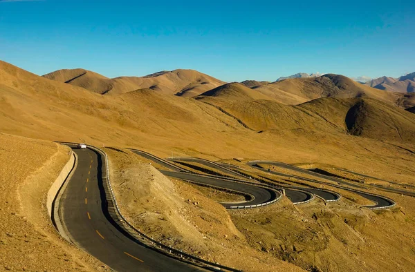 Carro prateado desce por uma estrada que atravessa o planalto tibetano. — Fotografia de Stock