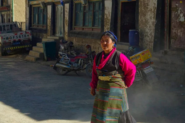 Κοντινό πλάνο: Τοπική Ασιάτισσα διασχίζει το σκονισμένο δρόμο σε μια αγροτική πόλη στο Θιβέτ — Φωτογραφία Αρχείου