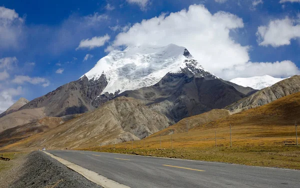 LOW Kąt: Pusta droga asfaltowa biegnie obok majestatycznego lodowca w Himalajach. — Zdjęcie stockowe