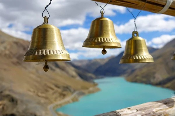 CLOSE UP: Three golden bells hang on top of hill overlooking Manak Dam Lake. — Stock Photo, Image