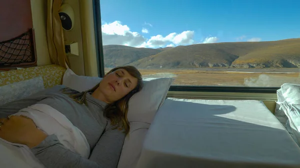 CLOSE UP: Young woman napping in the soft bed of overnight train crossing Tibet. — Stock Photo, Image