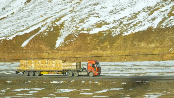 Rode vrachtwagen met een lading door besneeuwd Tibet op een zonnige herfstdag. — Stockfoto