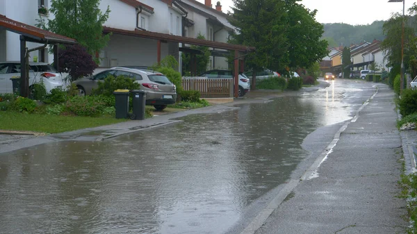 Yağmur suyu, sakin banliyölerdeki teraslı evlerin önünden geçen yolu kaplıyor. — Stok fotoğraf