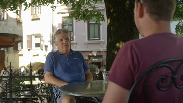 FERMETURE : Père et fils parlent assis dans un café par une journée ensoleillée d'été. — Photo