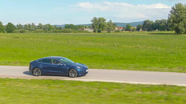 AERIAL: Modern tourists speed through the countryside in a brand new Tesla 3 — Stock Photo, Image