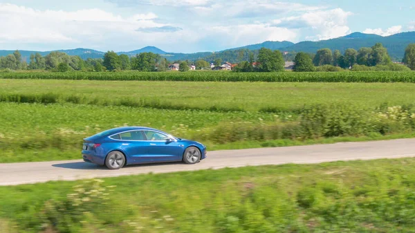 DRONE: Metallic blue Tesla drives along a scenic country road on a sunny day — Stock Photo, Image