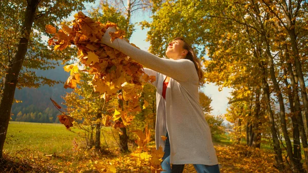 ZAMKNIJ: Szczęśliwa dziewczyna wyciąga ramiona jak kolorowe liście spadają z wierzchołków drzew — Zdjęcie stockowe