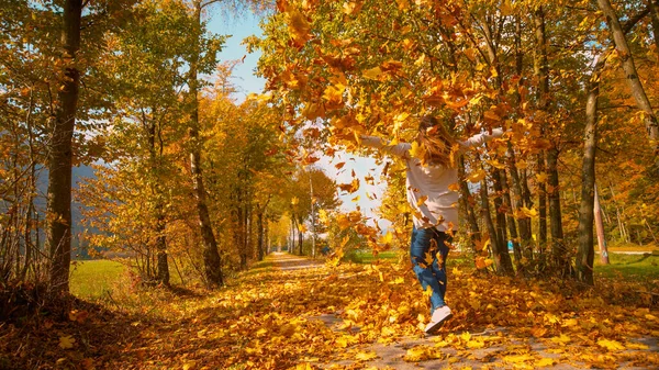 COPY SPACE Woman gira depois de jogar uma pilha de folhas coloridas de outono no ar — Fotografia de Stock