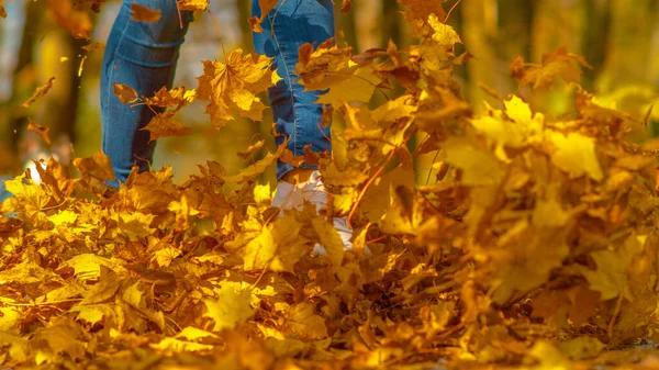 LOSE UP: Oigenkännlig flicka sparkar blad när hon går genom färgglada skogar — Stockfoto