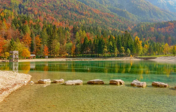 Большие камни создают тропу через красивое озеро у красочного леса. — стоковое фото