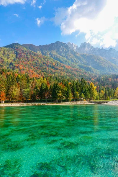 Espectacular tiro de colorido bosque cubierto de montaña que se eleva sobre el lago esmeralda. —  Fotos de Stock