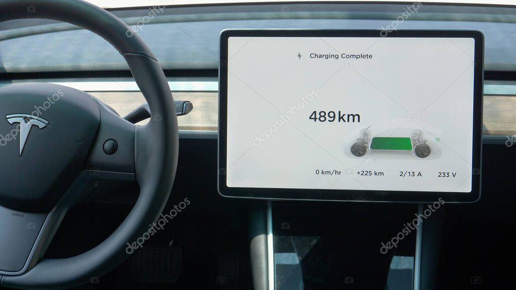 TESLA, VIENNA, AUSTRIA, JULY 2019: CLOSEUP Touchpad inside Tesla car displays the battery charging is complete. High tech autonomous car is fully charged. Futuristic car interior with tablet display