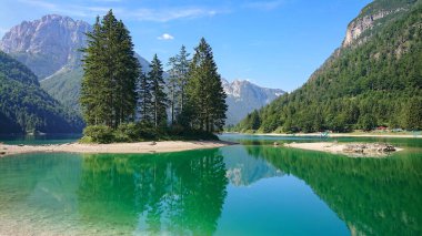 Kayalık dağların altındaki zümrüt renkli gölün muhteşem manzarası.