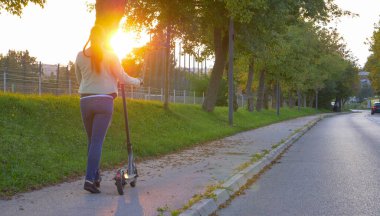 Genç bir kadın, motorsikletinin elektriği bitince sinirlenir.