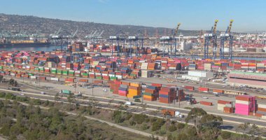 Los Angeles 'ın renkli limanından geçen otoyol boyunca arabalar ve kamyonlar sürüyor.