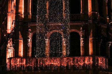 Turuncu renkli Noel ışıkları tarihi binanın balkonunu aydınlatıyor..