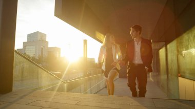 İş ortakları güneşli finans bölgesinde yürürken sohbet ediyorlar.