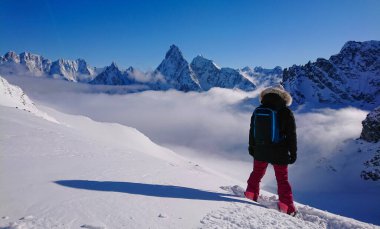 Snowboardcu taze karı parçalamadan önce karlı sırtı gözlemliyor..