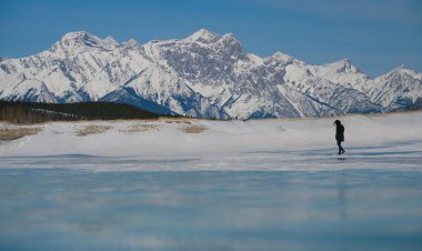 Tanımlanamayan turist Rocky Dağları 'ndaki donmuş bir gölde yürüyor.