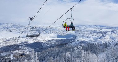 Park City 'de kayak yapan iki turist dağın tepesine çıkmak için teleferiğe biniyor..