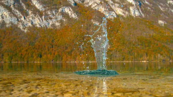 Scenic shot van een rots vallen in een smaragd meer en het maken van een plons — Stockfoto