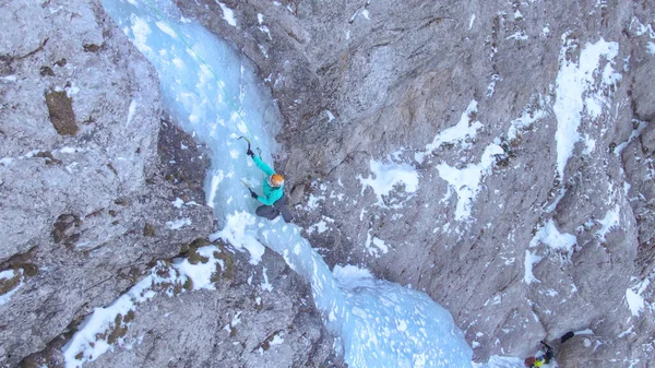 DRONE: Dişi dağcı buz kıracağını yerleştirirken buz şelalesine tırmanıyor. — Stok fotoğraf