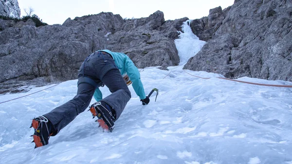 AMBOS: Mujer escalando hielo en los Alpes Julianos se detiene y mira sus crampones — Foto de Stock