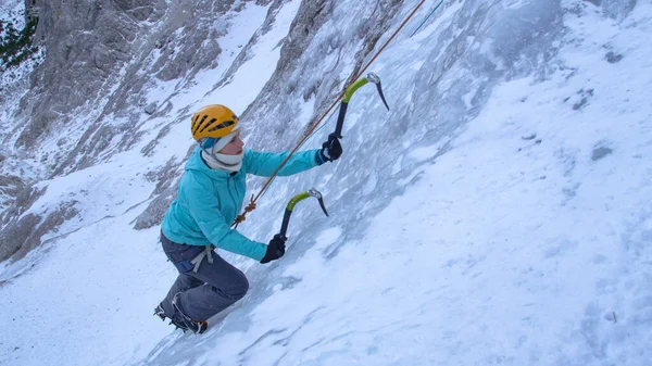 CLOSE UP: Young female alpinist scales up dangerous frozen waterfall in the Alps — Stock Photo, Image