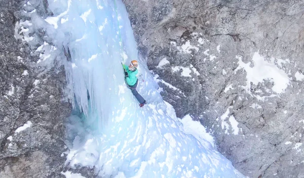 Mujer colocando cuidadosamente sus hachas de hielo mientras sube por una cascada helada — Foto de Stock