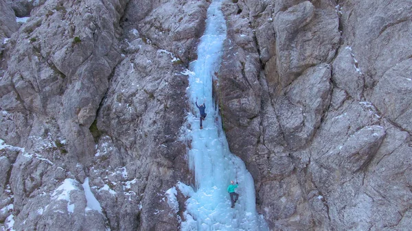DRONE Létající ke skalnaté stěně jako dva horolezci šplhají po zamrzlém vodopádu — Stock fotografie
