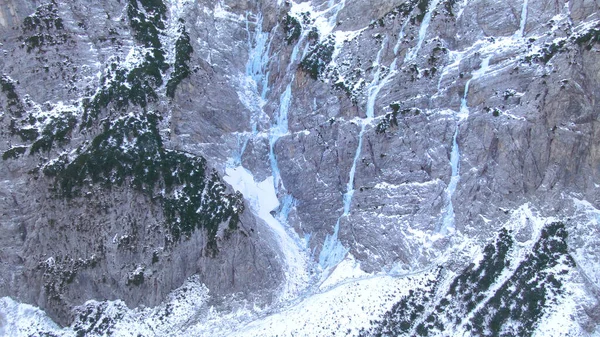 AERIAL Flying towards a rocky cliff and frozen waterfalls in Slovenian mountains — ストック写真