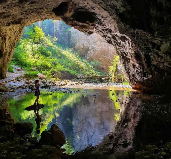 Ung kvinnlig vandrare står på en sten och underverk vid karstgrottan i Slovenien. — Stockfoto