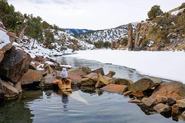 CLOSE UP Girl in a bikini and cap lies in hot pond and observes the snowy nature