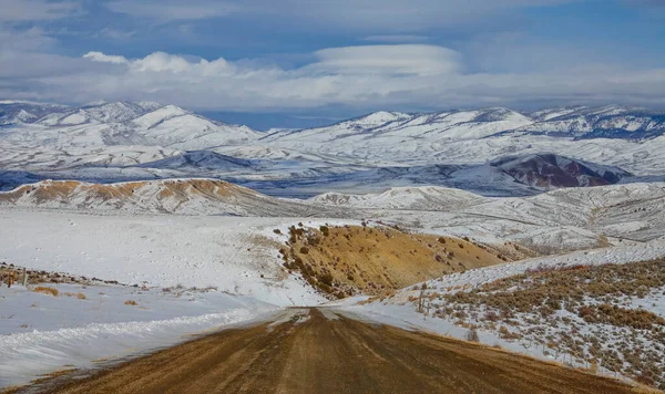 Bevroren onverharde weg kruist de adembenemende sneeuw bedekt wildernis van Colorado. — Stockfoto