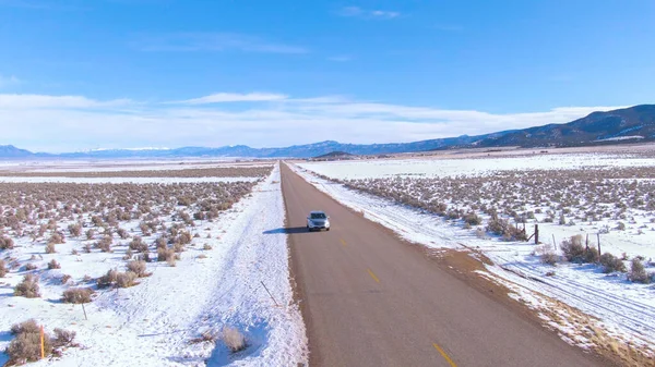 AERIAL: Turistas em uma divertida viagem de carro de inverno ao longo da estrada cênica em Montana — Fotografia de Stock