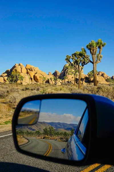 VERTICAL: Боковое зеркало автомобиля предлагает потрясающий вид на национальный парк Джошуа Три — стоковое фото