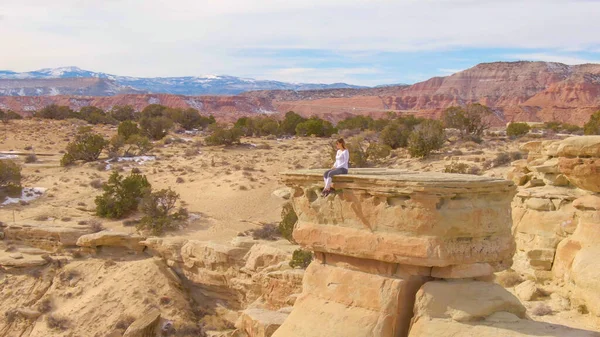 DRONE : Jeune grimpeur assis au bord d'une formation rocheuse surplombant le désert — Photo