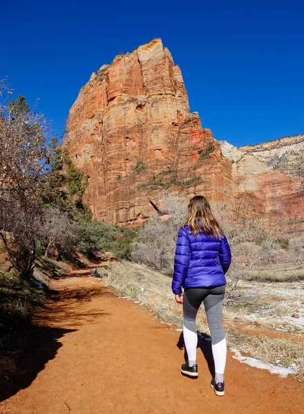 VERTICAL : Une jeune femme marche le long d'un sentier de terre sous la montagne de grès — Photo