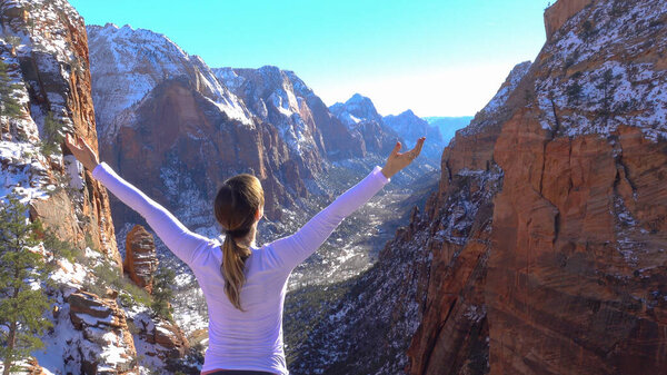 CLOSE UP: Carefree woman raises her arms after hiking up to Angel's Landing.